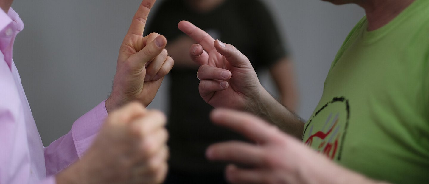 Zwei Männer stehen sich im Gespräch gegenüber und gestikulieren angeregt.