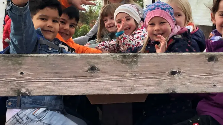 Die Kinder der KiTa fahren mit einem Planwagen.
