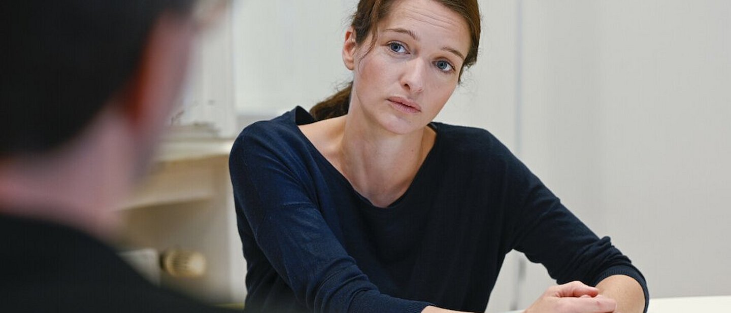 Eine Frau und ein Mann sitzen zusammen am Tisch und unterhalten sich.