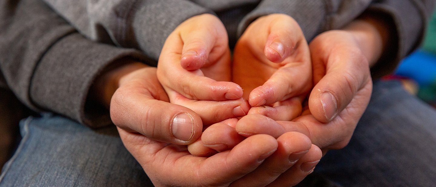 Jung und Alt halten ihre geöffneten Hände ineinander.