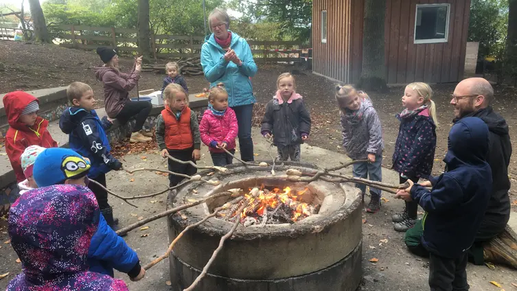 Auf dem Foto sieht man die KiTakinder um das Lagerfeuer beim Stockbrotgrillen.