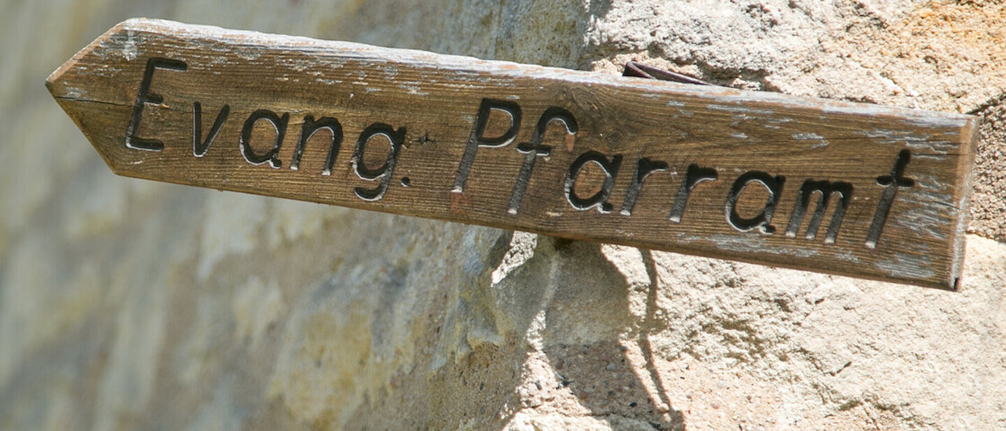 An der Ecke einer Steinmauer befestigt. Pfeil deutet nach links