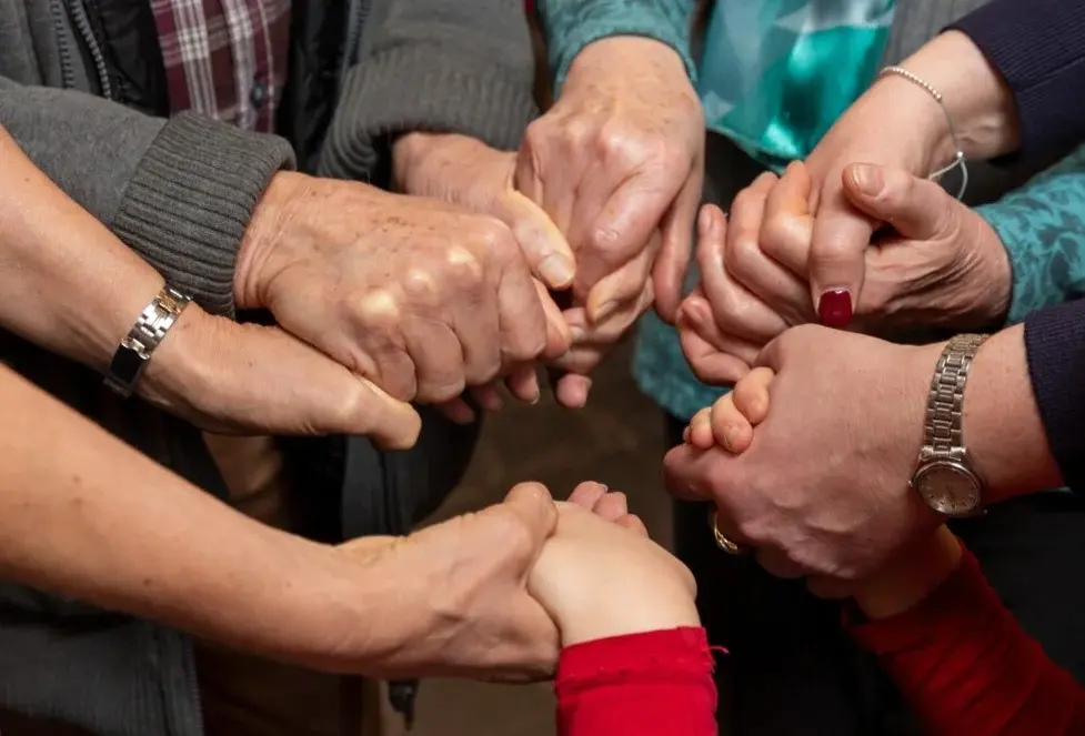 Gruppe Betender, die sich an den H#nden halten.