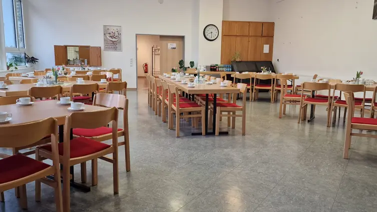 Saal mit Tischgruppen und Stühlen