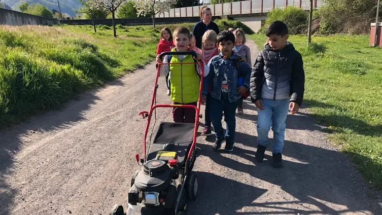 Die KiTa-Kinder mit dem Rasenmäher auf dem Weg in den KiTa-Garten.