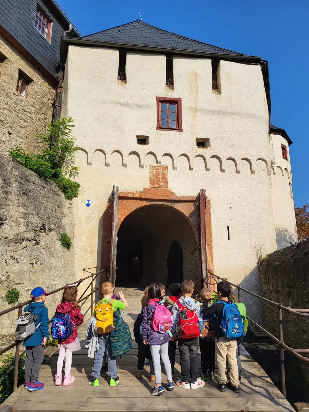 Das Foto zeigt die Kinder der Eisbärengruppe vor dem Tor der Marksburg.
