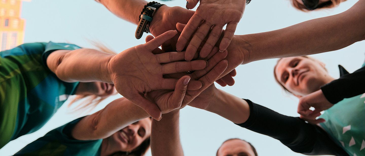 Gruppe von Menschen, die sich an Händen hält.