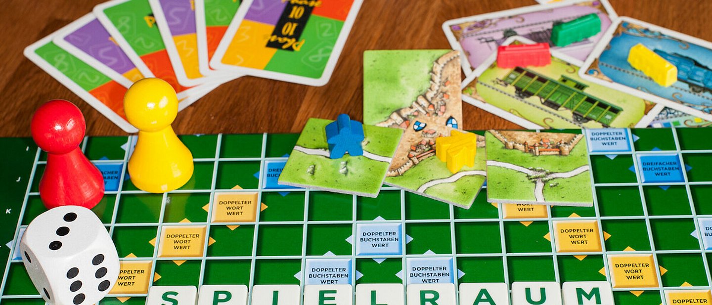 Verschiedene Spiele ausgebreitet, mit Würfel, Spielfiguren und Karten