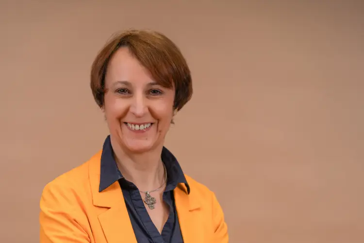 Birgit Hamrich, kurze dunkle Haare, dunkle Bluse, heller Blazer, lächelt in die Kamera