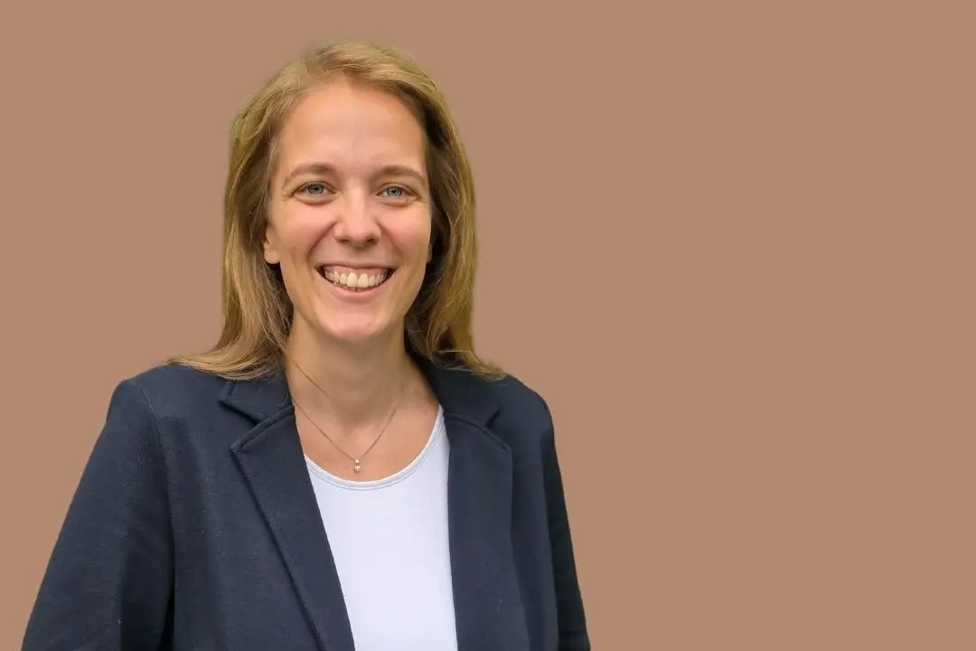 Marian Wachter, offenes Lachen, blonde lange Haare, trägt T-Shirt und Blazer, lacht in die Kamera
