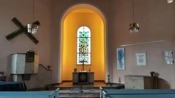 Innenraum der Stadtkirche mit Blick auf den Altar und das kunstvolle Buntglasfenster