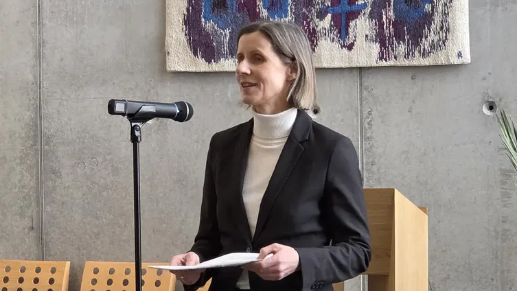 Frau Stewen steht an einem Mikrofon und redet