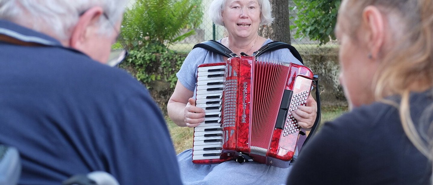 Dorothee Ewald spielt Akkordeon die Besucher*innen des Treffs.