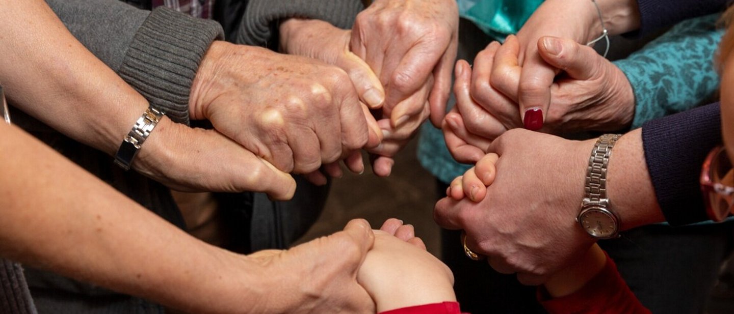 Gruppe Betender, die sich an den H#nden halten.