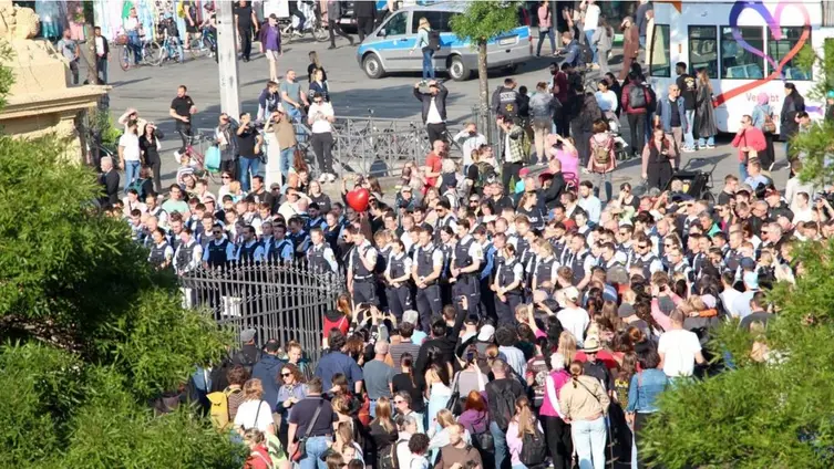 Viele Menschen versammeln sich auf einem Platz. Dabei sind viele Polzisten und Polizistinnen.