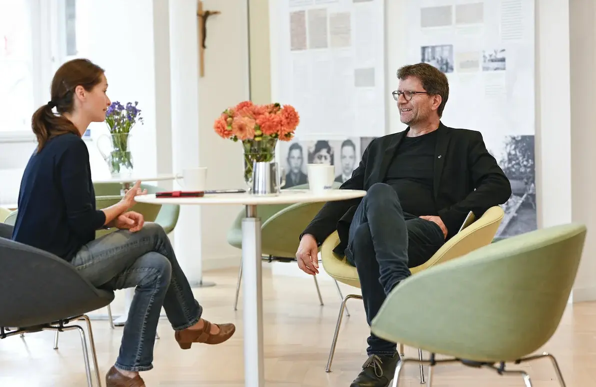 Eine Frau und ein Mann sitzen zusammen am Tisch und unterhalten sich.