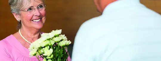 Foto einer Frau, die Blumen überreicht bekommt