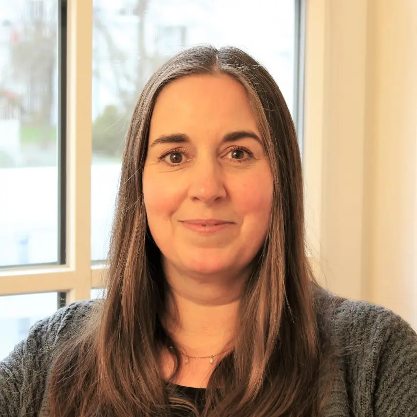 Frau mit langen dunklen Haaren vor einem Fenster