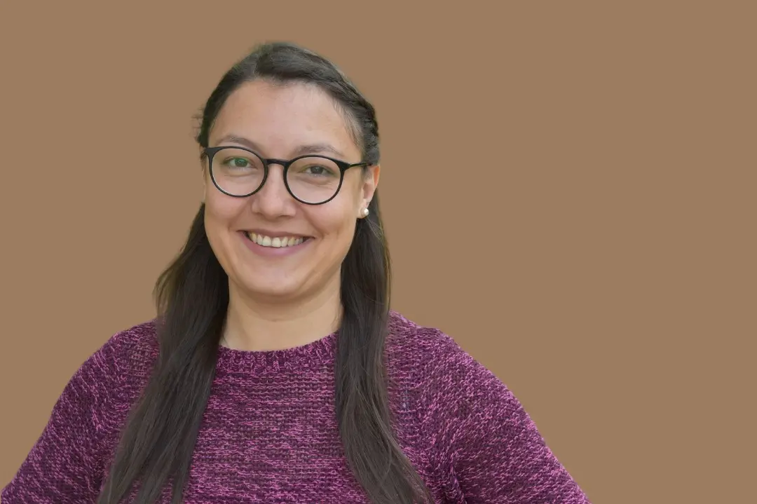 Porträtaufnahme von Margarita Kappl, junge Frau, lange dunkle Haare, die sie zurückgekämmt trägt, Brille, freundliches und offenes Lächeln