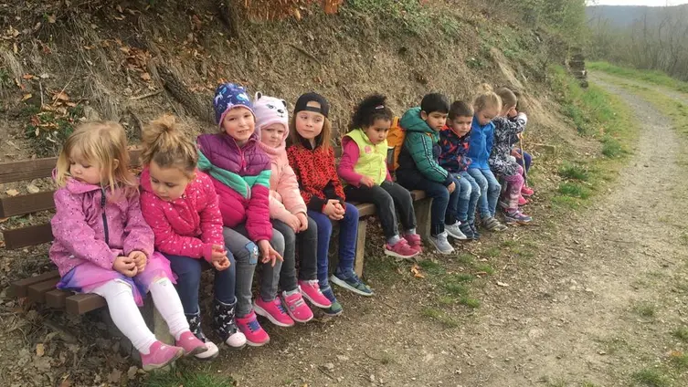 Das Foto zeigt eine Gruppe von KiTakindern auf einer langen Ruhebank.