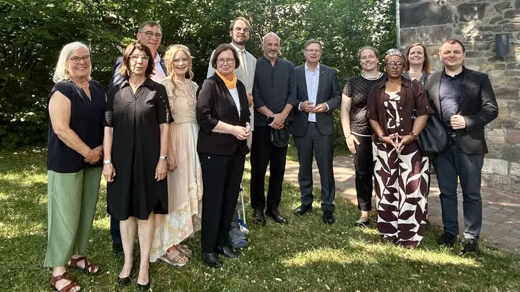 Viele Menschen im Halbkreis stehend und blicken in die Kamera