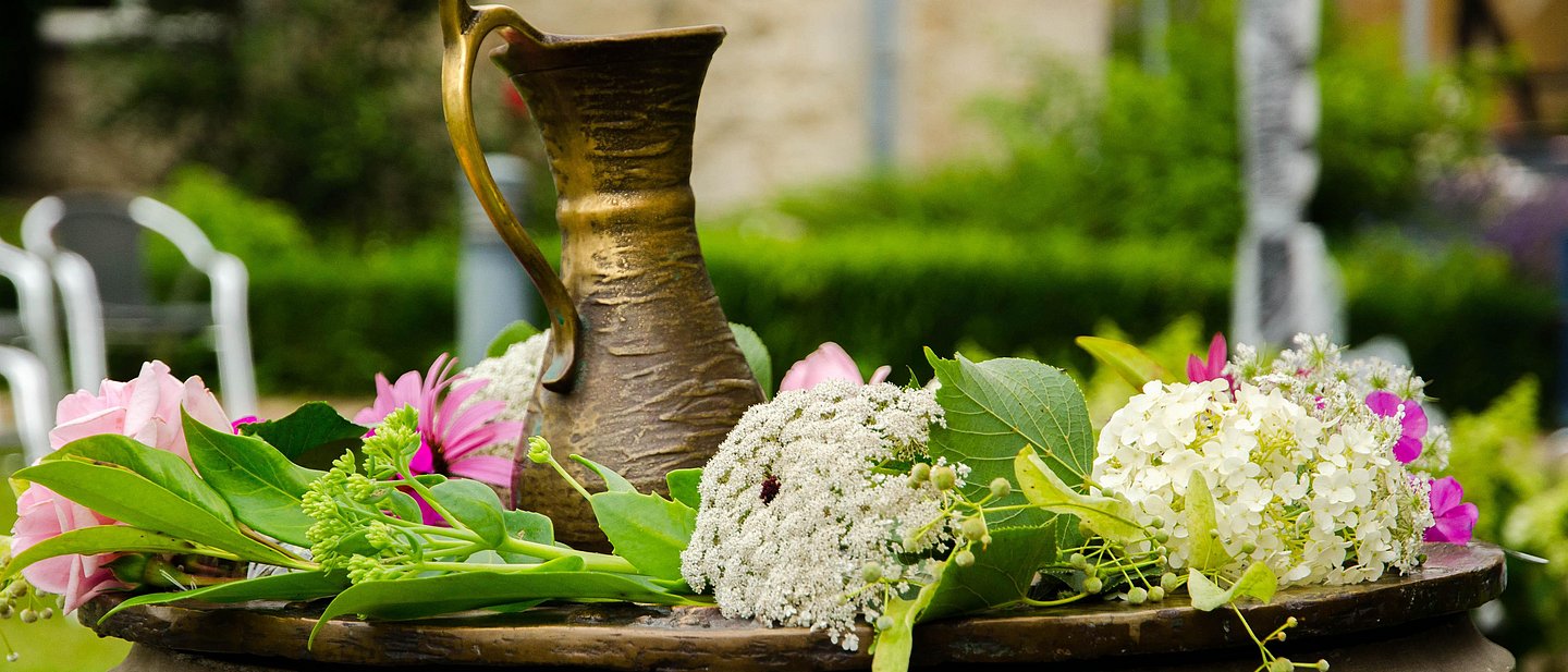 Mit Blumen geschmücktes Taufbecken im Kirchgarten