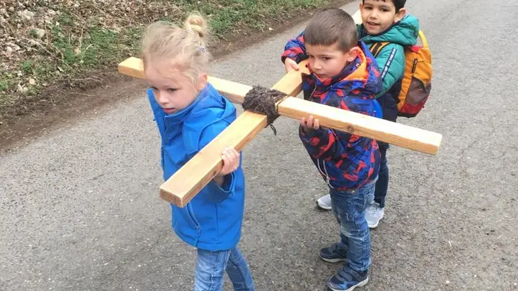 Das Foto zeigt die Kinder der Kindertagesstätte die ein Holzkreuz auf ihren Schultern tragen.