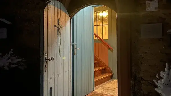 Kirchentür Laurentiuskirche Arnoldshain Die blaue Kirchentür der Laurentiuskirche Arnoldshain von außen. Die Tür ist offen, die Lichter im Eingang strahlen auf den Schnee vor der Tür. An der Innenseite der Tür ist ein Kreuz aufgehängt.