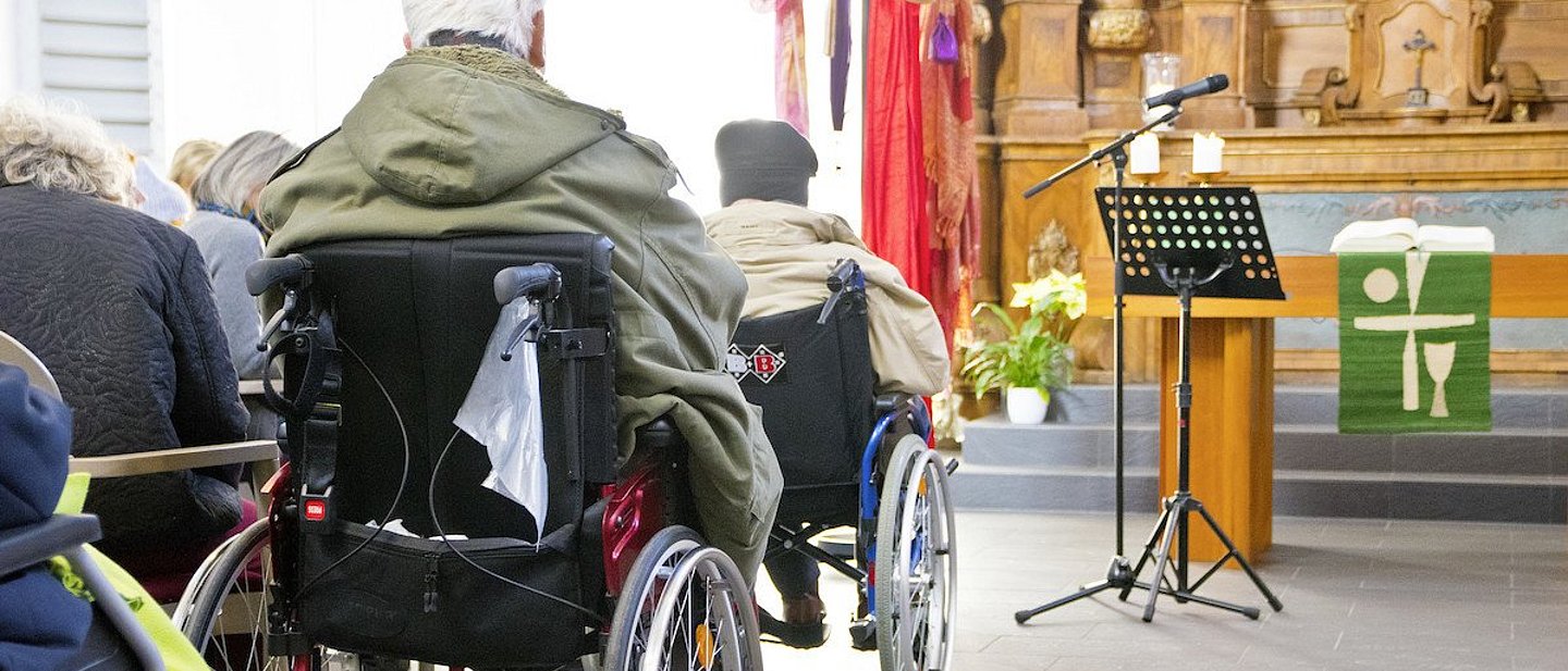 Menschen im Rollstuhl in einer Kirche.
