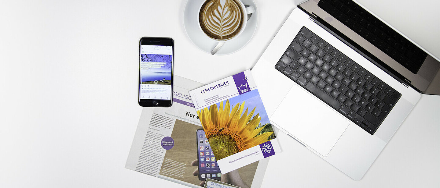 Ein Fundus Flyer, Laptop, Zeitung, Smartphone und eine Tasse Kaffee liegen auf einer weißen Fläche.