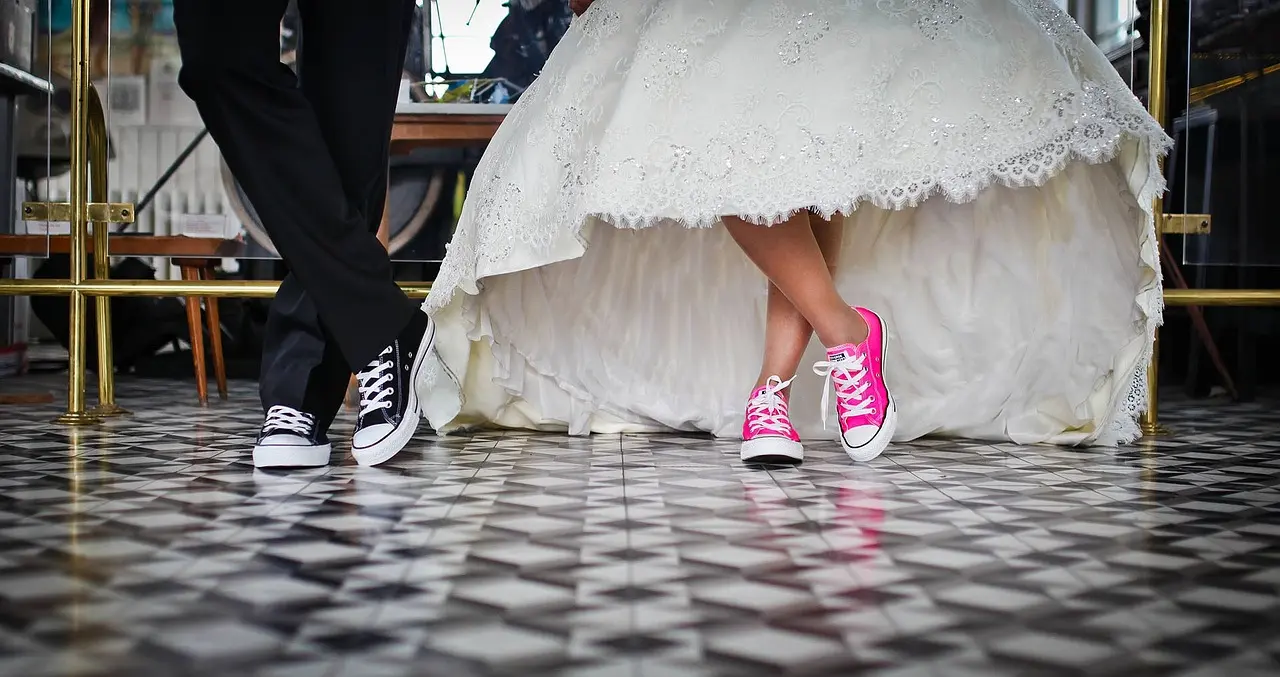 Hochzeitspaar mit pinken und schwarzen Chucks. Es sind nur Beine und Füße zu sehen.