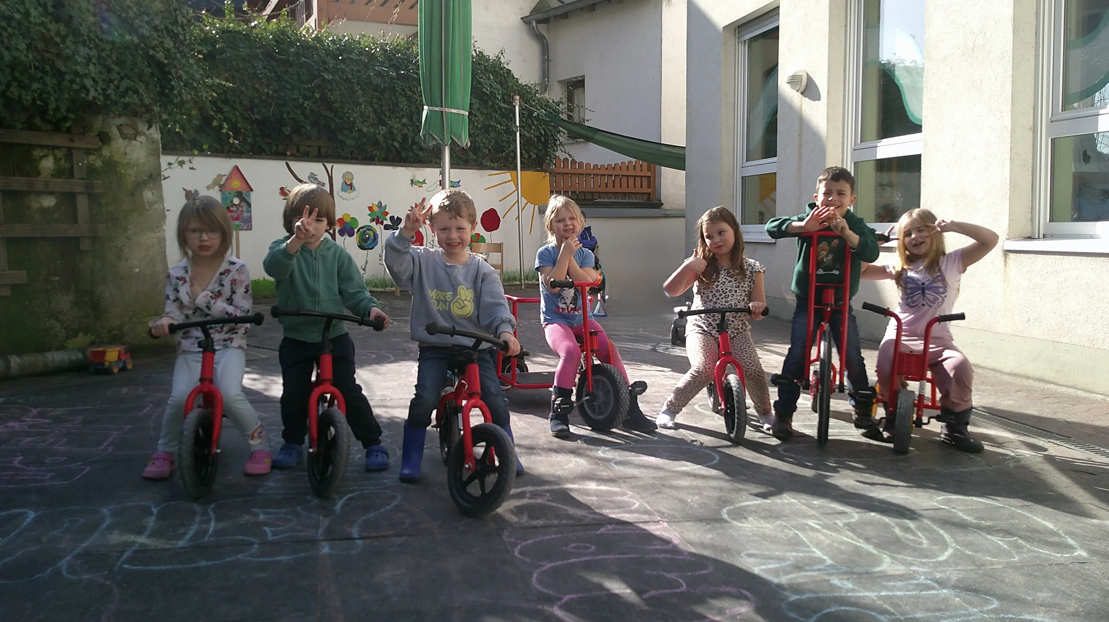 Auf dem Foto sieht man strahlende Kinder der KiTa auf den neu angeschafften Fahrzeugen.