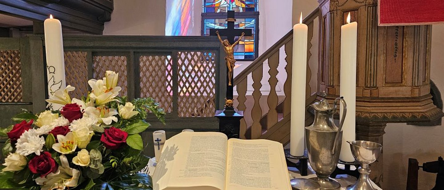 Altar mit Bibel, Blumen und Kerzen sowie Abendmahlsgerät