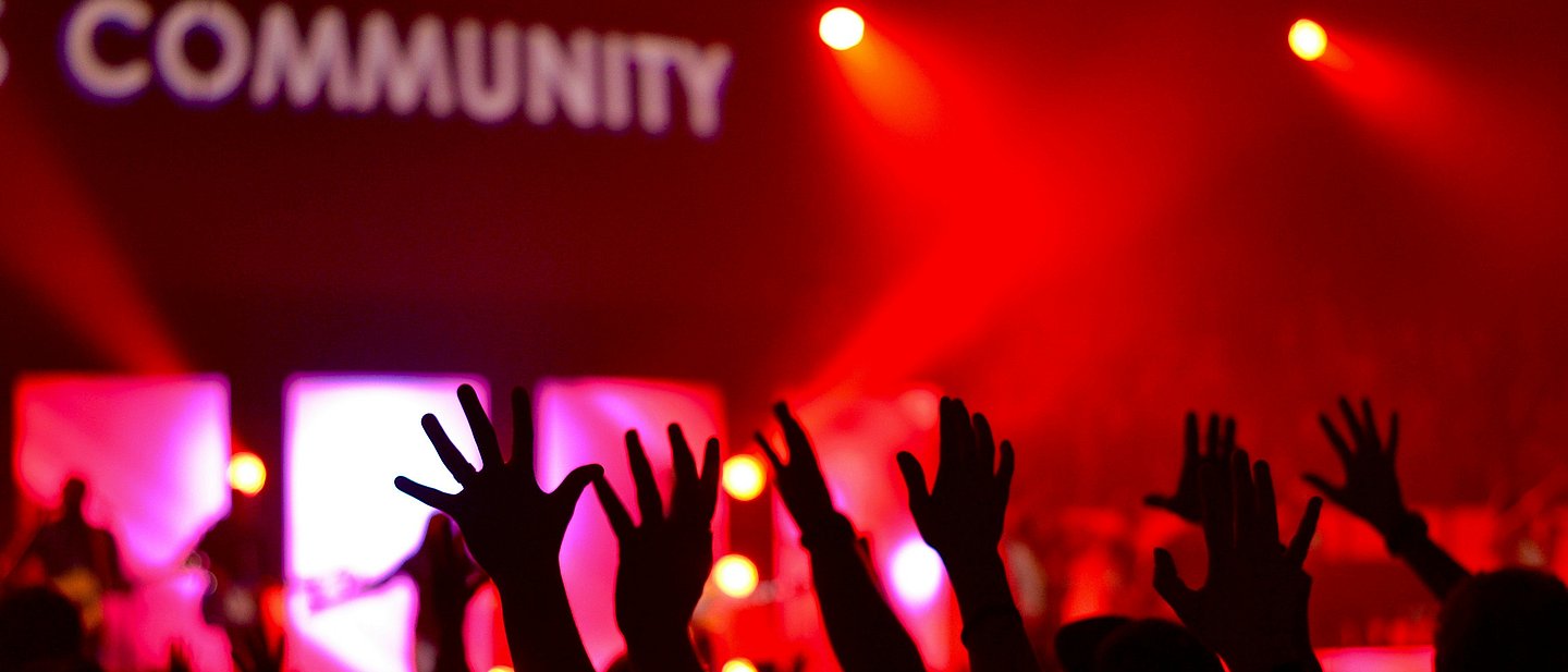 Menschen feiern gemeinsam vor dem Schriftzug "Community"