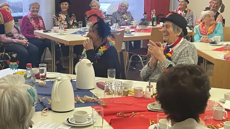 Fastnachtlich gekleidete Seniorinnen lachen herzhaft beim närrischen Seniorennachmittag im katholischen Pfarrheim Ginsheim