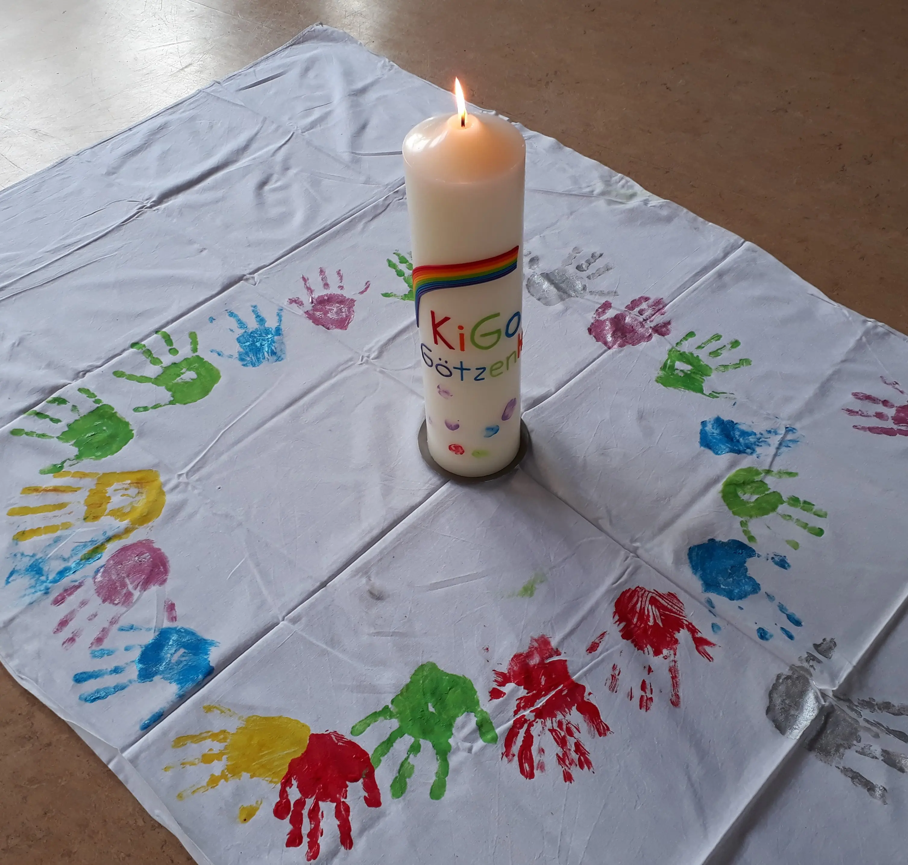 Decke mit einem Kreis aus Kinderhandabdrücken aus Fingerfarbe in der Mitte ien brennende Kernze