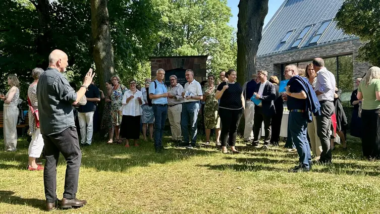 Andreas Lipsch und seine Gäste stehen im Halbreis vor ihm auf einer Wiese. 