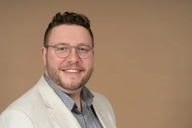 Porträt Tobias Vonderlehr, kurze dunkle Haare, Brille, Bart, Hemd und helles Jackett