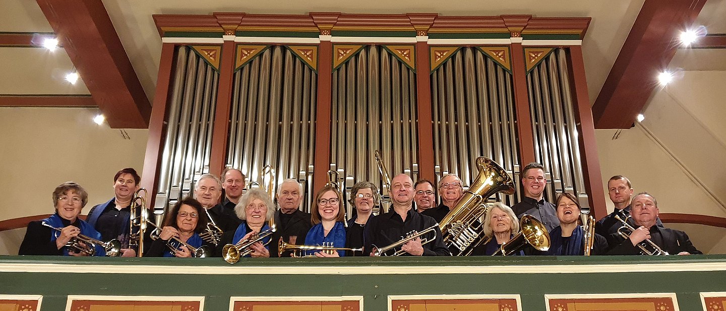 Die Mitglieder der Praunheimer Bläserey schauen von der Orgelempore herab ni die Kamera. 