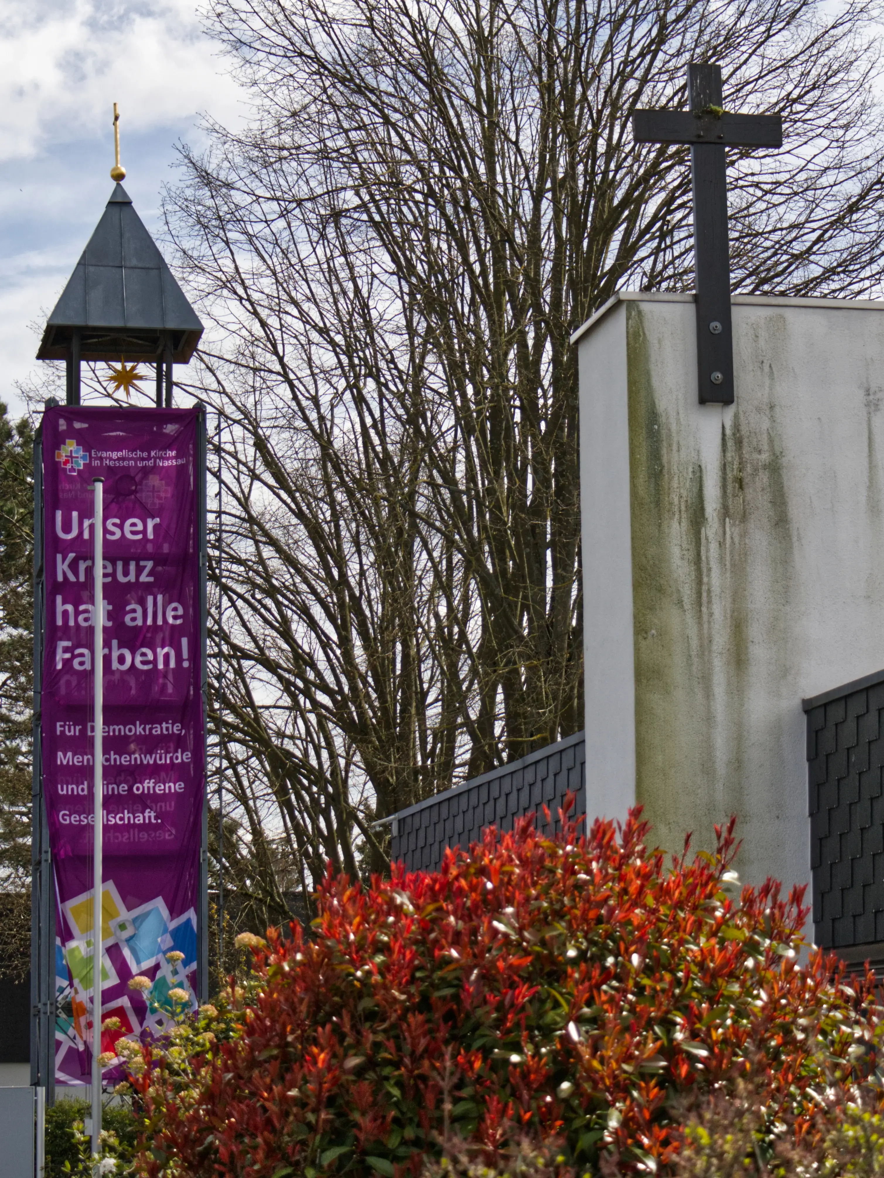 Evanglische Kirche in Ober-Erlenbach mit "Unser Kreuz hat alle Farben" Fahne am Glockenturm