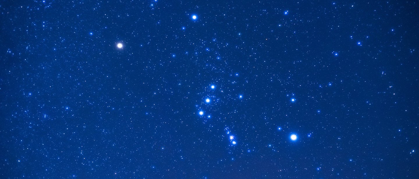 Am dunkelblauen Nachthimmel sind viele Sterne zu sehen, deutlich vor allem das Sternbild Orion.