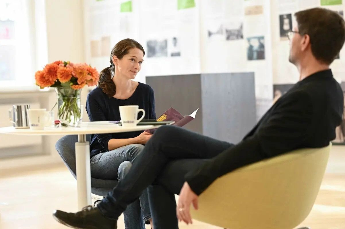 Eine Frau und ein Mann sitzen zusammen am Tisch und unterhalten sich.