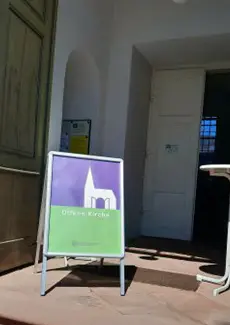 Eingang zur Hugenottenkirche Friedrichsdorf mit dem Schild "Offene Kirche"